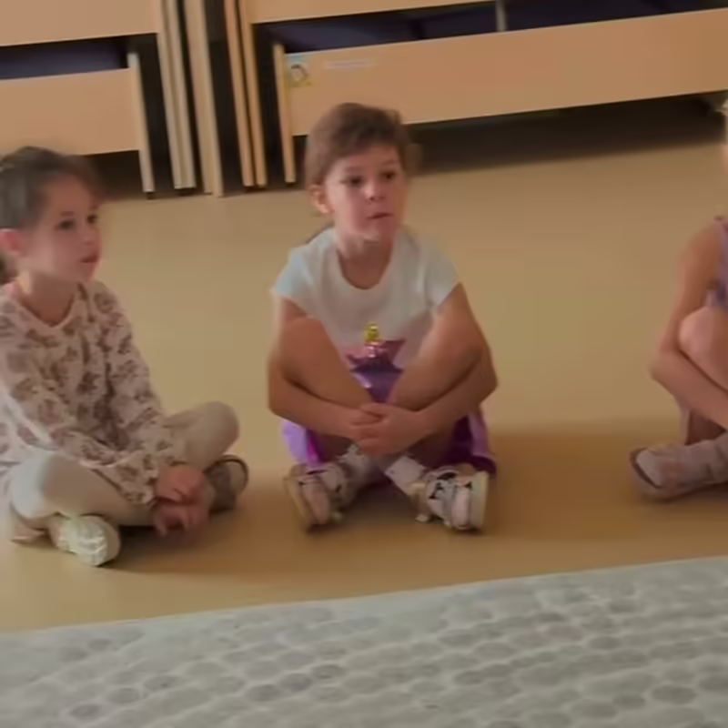 Дети сидят на полу в кругу и слушают историю