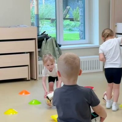 Дети с мячами и конусами на занятии по футболу в детском саду на Судостроительной